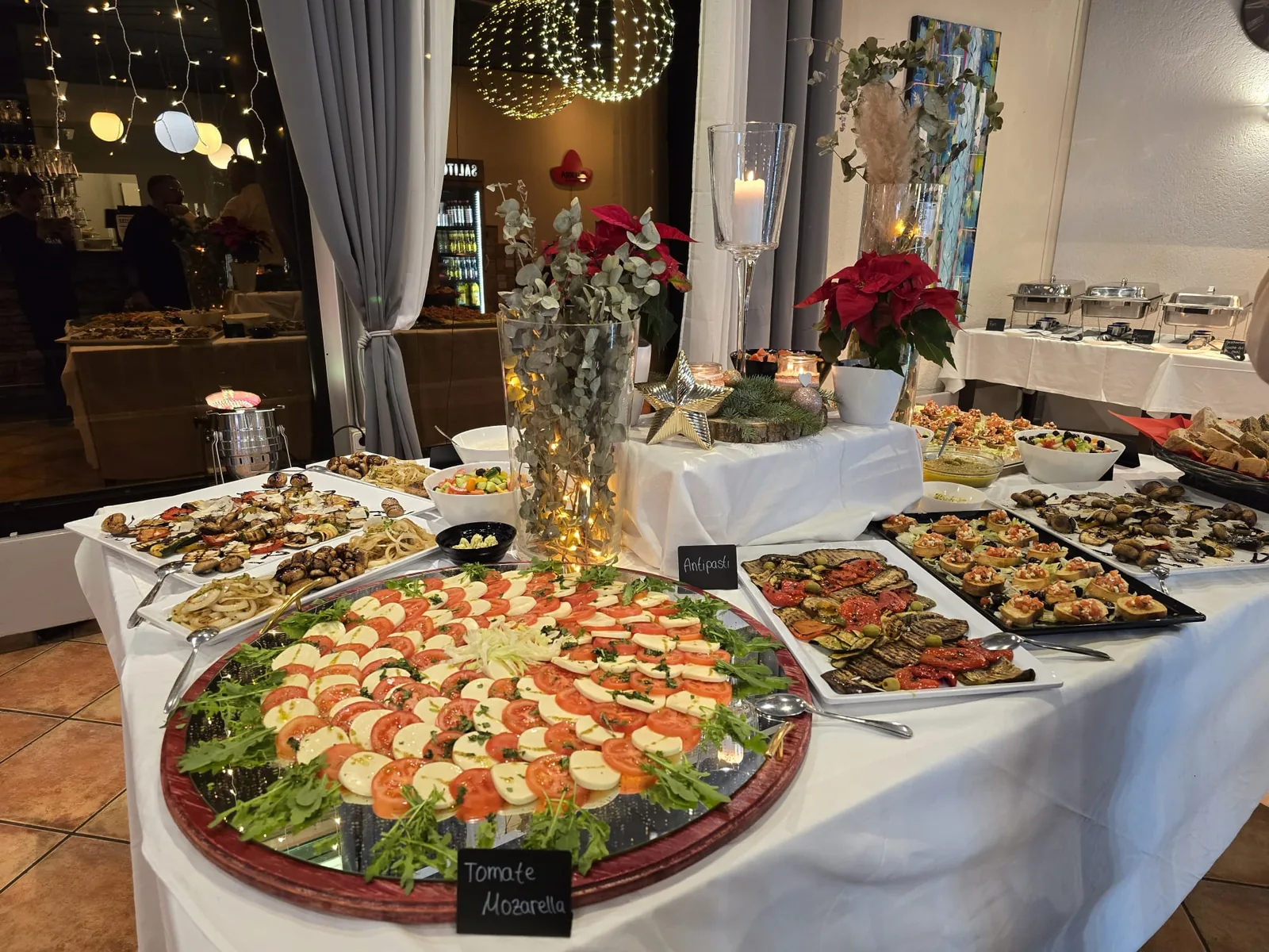 Festlich dekoriertes Buffet mit runder Tomate-Mozzarella-Platte