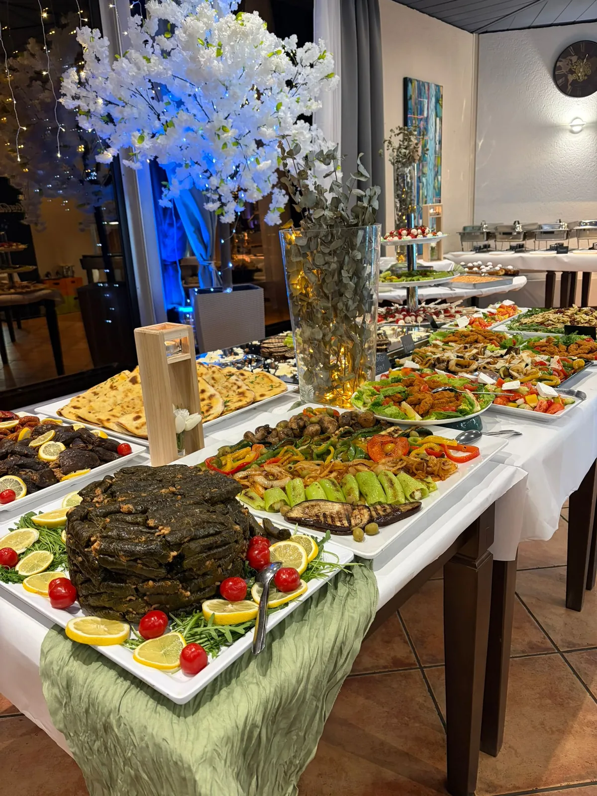 Buffettafel mit Vorspeisen, gefüllten Weinblättern, Fladenbrot und gegrilltem Gemüse