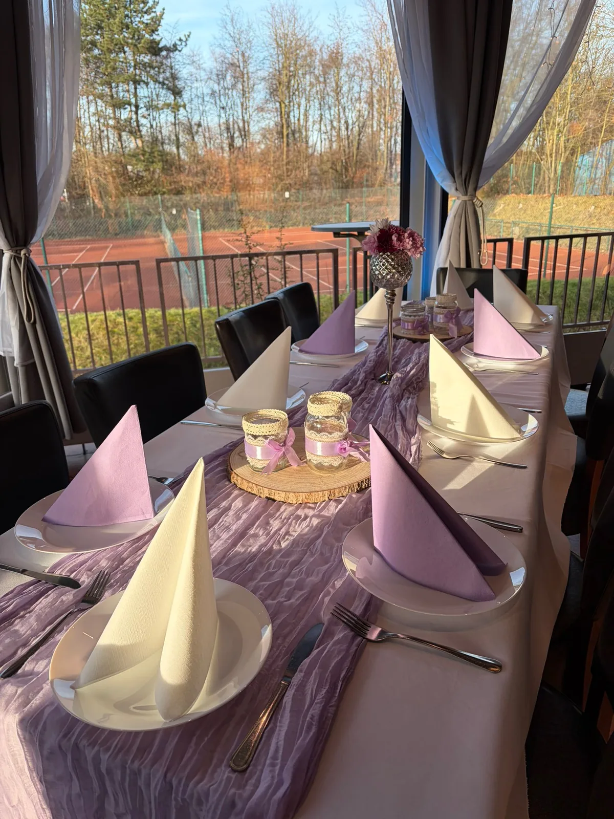 Festtafel mit fliederfarbenem Läufer, Windlichtern und Blumenschmuck