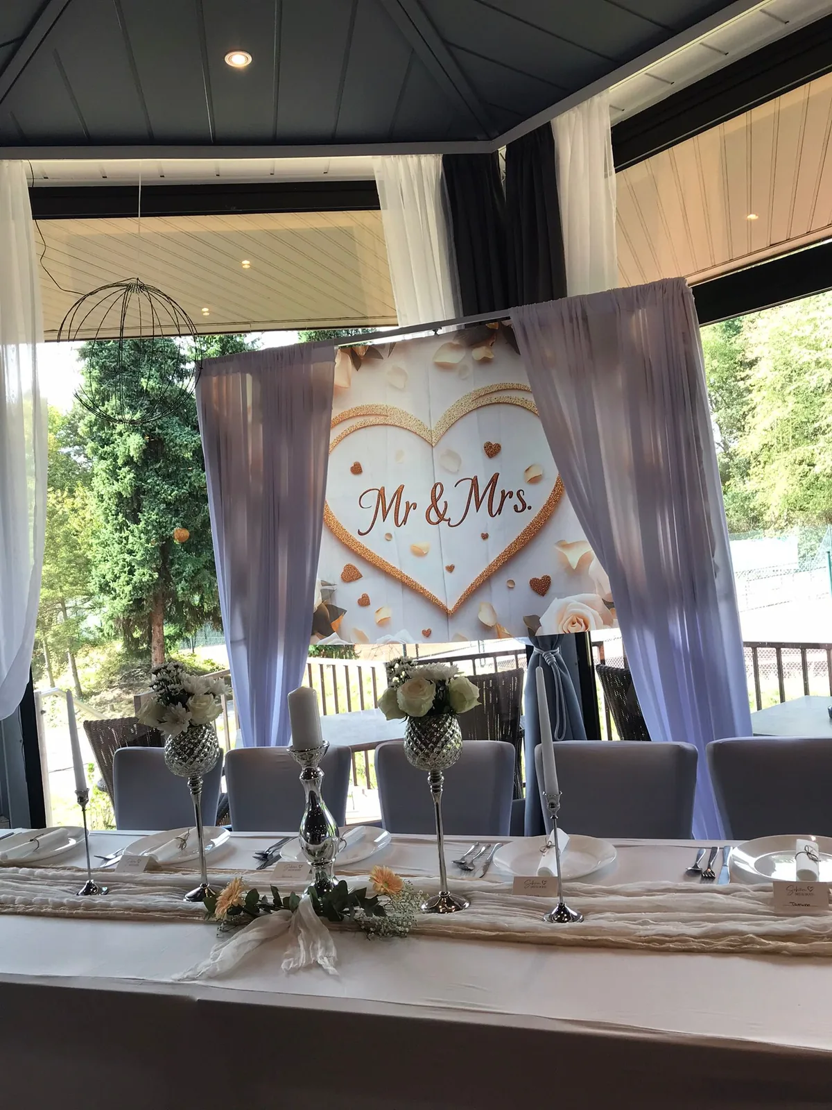 Brauttafel mit Mr-und-Mrs-Banner und weißen Vorhängen