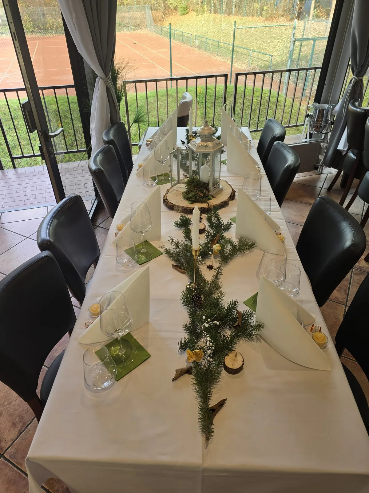 Lange Tafel von oben mit Laterne auf Holzscheibe und Tannengrün