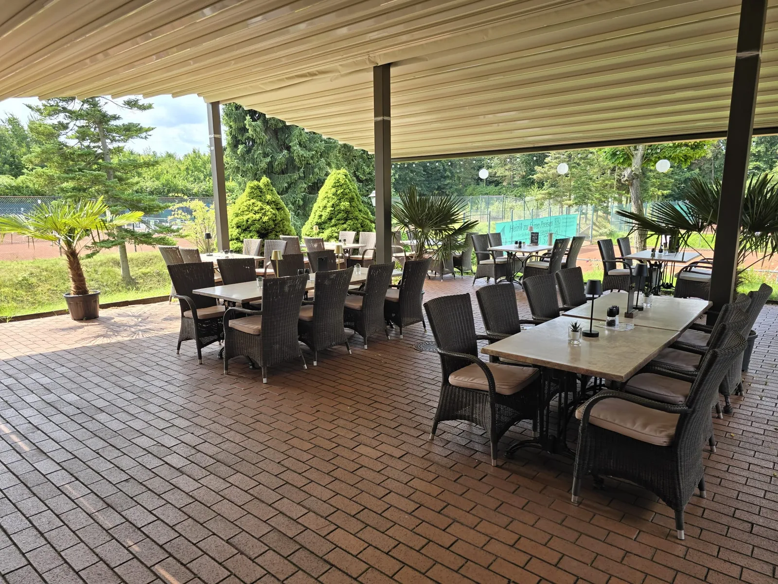 Überdachte Terrasse mit Rattanstühlen und Blick ins Grüne